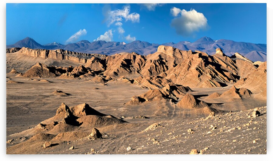 Rugged desert mountains under a clear blue sky with clouds. by Marco Brivio