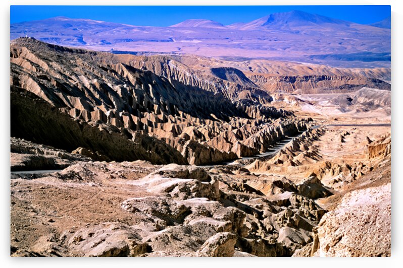 Eroded desert landscape with a road winding through mountains. by Marco Brivio