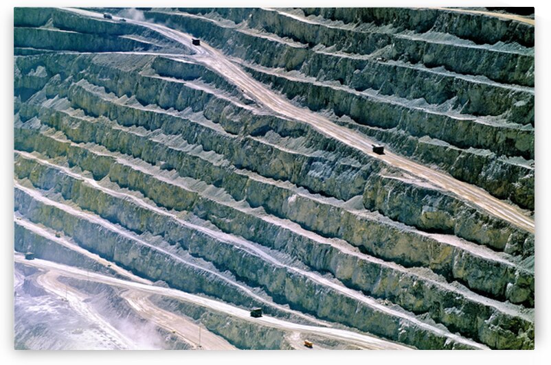 Large open pit mine showing terraced levels and mining trucks. by Marco Brivio