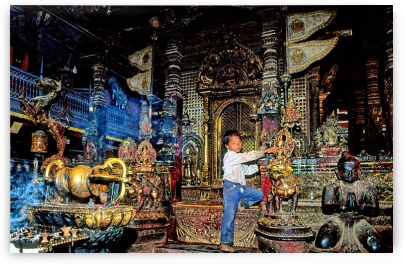 Boy interacts with religious artifacts in Kathmandu temple by Marco Brivio