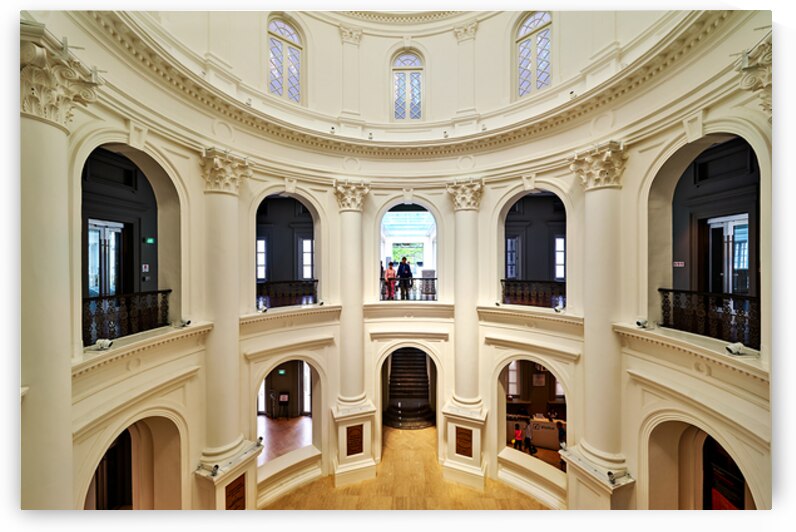 People walk and observe inside the National Museum of Singapore. The architecture shows classic design features. by Marco Brivio