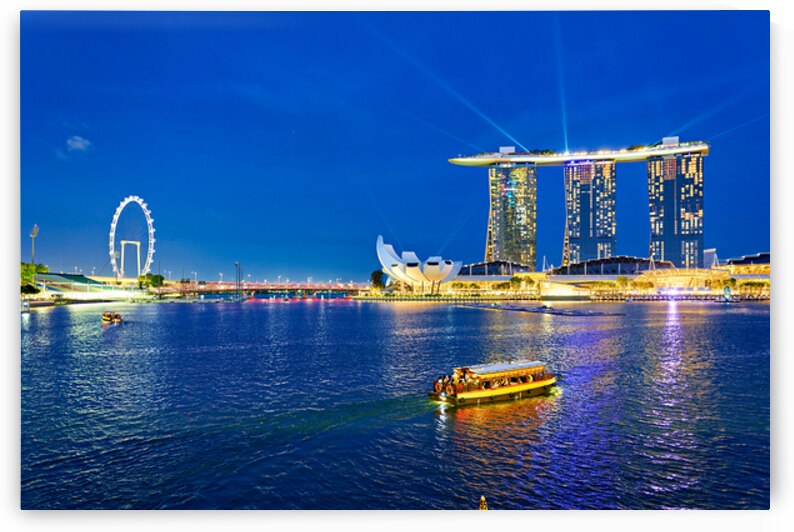 Skyline view of Marina Bay at sunset with people by the water by Marco Brivio