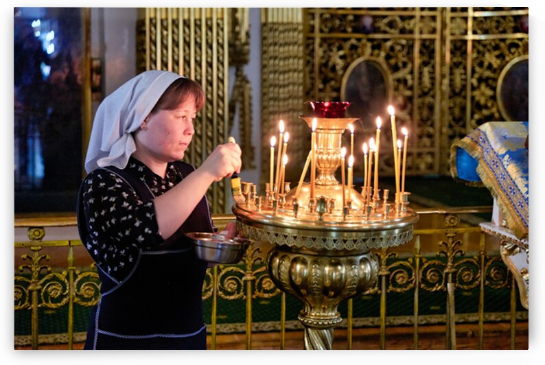 A woman lights candles in Transfiguration Cathedral in St by Marco Brivio