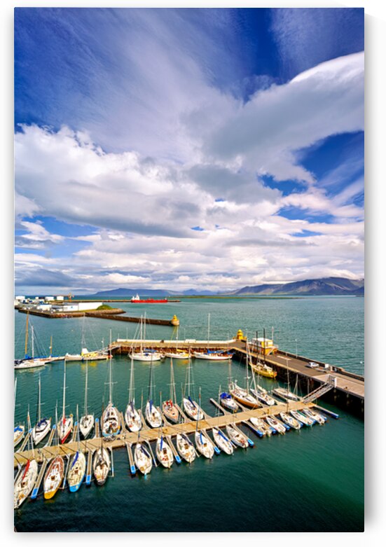 Sailboats docked in Reykjavik harbor under cloudy sky by Marco Brivio