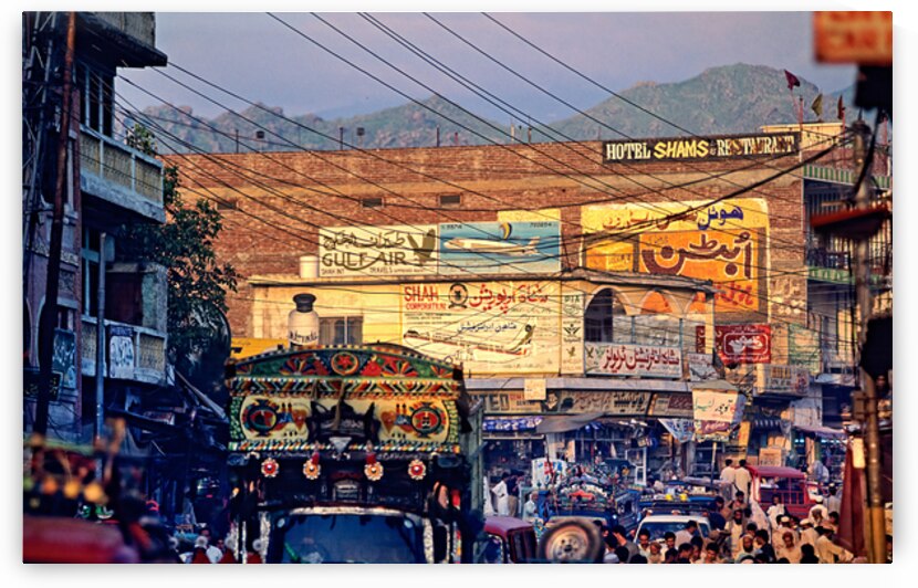 Busy market scene in Mingora Pakistan with vehicles and shops by Marco Brivio