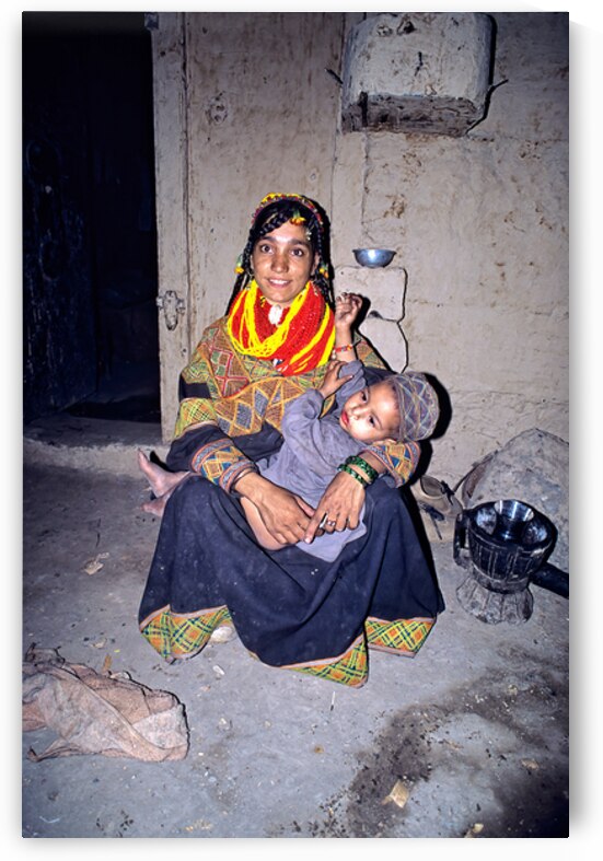 A woman holds her child in a Kalash village by Marco Brivio