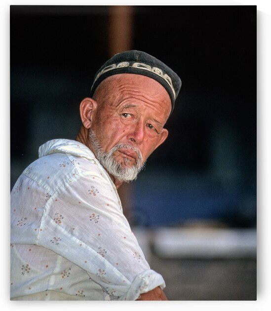 Man in traditional attire sitting in Bukhara Uzbekistan by Marco Brivio