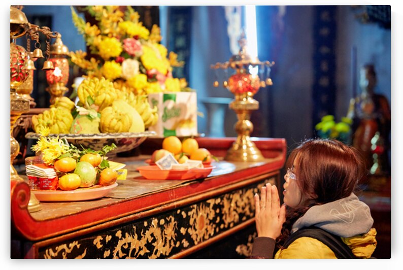 Person offers prayers at altar with fruits in Ho Chi Minh by Marco Brivio