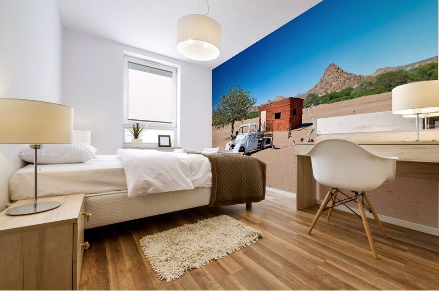 Classic car wreck in Namibias desert landscape near a structure Mural print