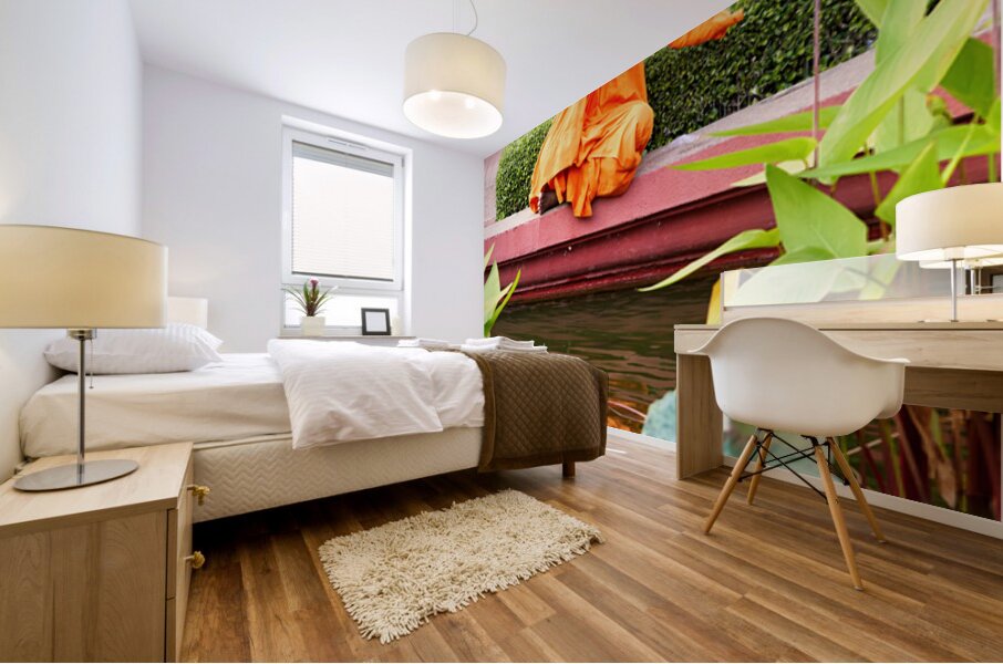 Monk in orange robes takes photo by a lotus pond. Mural print