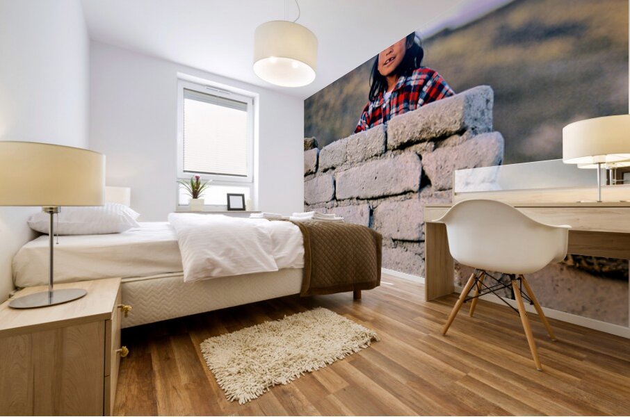 Young girl smiles over stone wall at sunset. Mural print