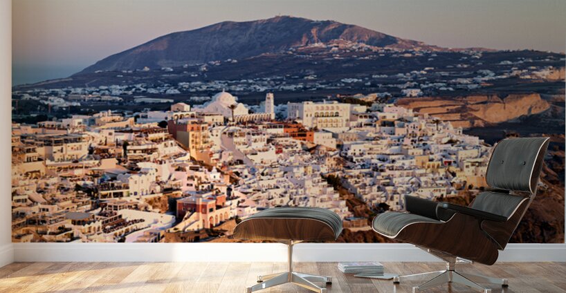 Santorini cliffside town at sunset with mountain backdrop. Wall Murals
