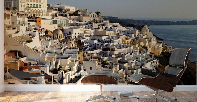Santorinis white buildings cascade down cliff to the sea. Wall Murals