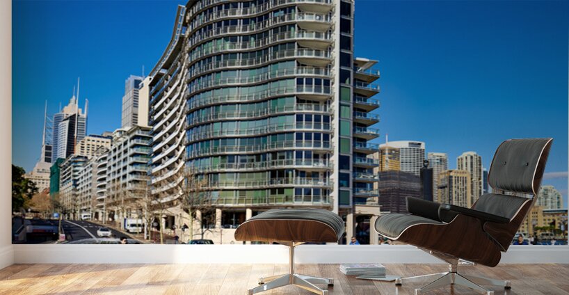 Modern curved building with balconies and city skyline. Wall Murals