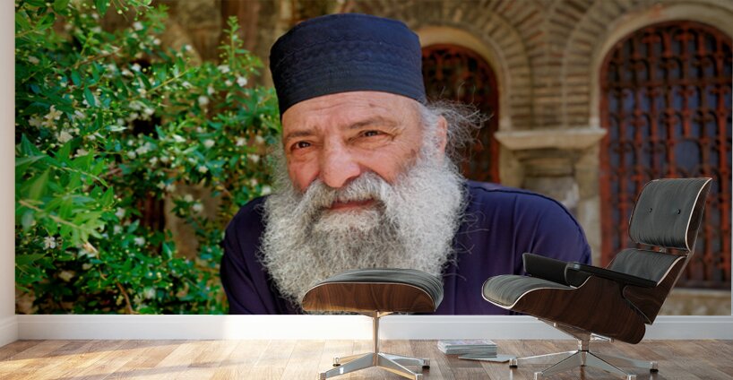 Elderly man with a beard poses near a historical building in a g Wall Murals