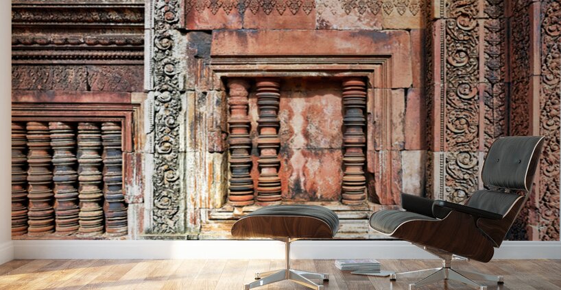 Ancient temple wall with intricate reddish stone carvings and co Wall Murals