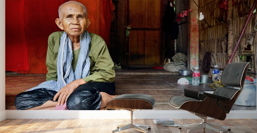 Elderly person sitting on floor in rustic dwelling. Wall Murals