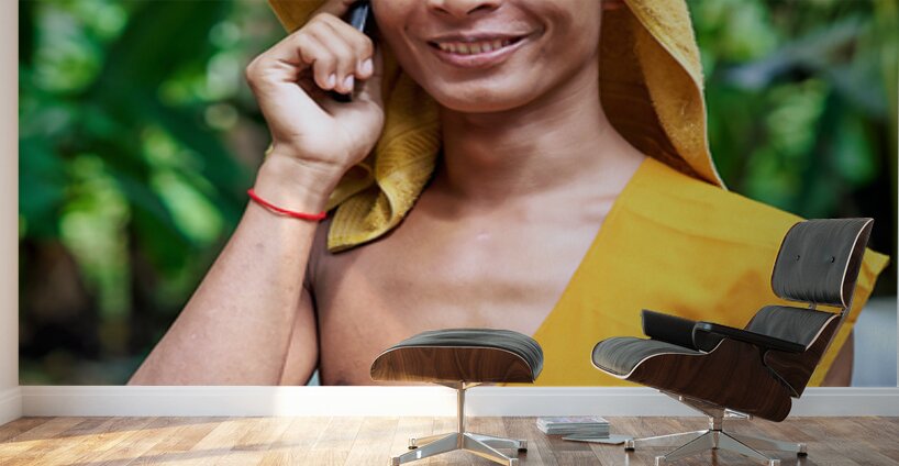 Smiling monk talks on phone with towel on head. Wall Murals