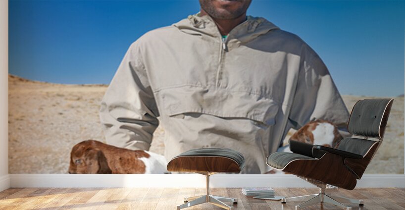 Shepherd holds his young goats in Namibia under bright blue sky Wall Murals