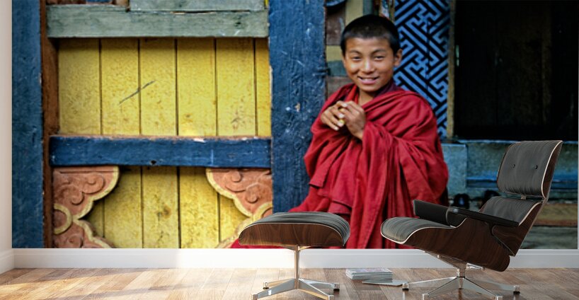 Smiling young monk in red robes at colorful traditional building Wall Murals