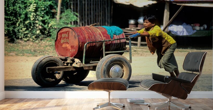 Boy pushes a cart down the street in Myanmar during the day Wall Murals