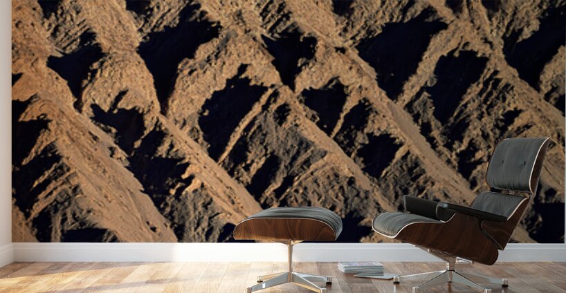 Hiker traverses a dramatic shadowed desert landscape. Wall Murals