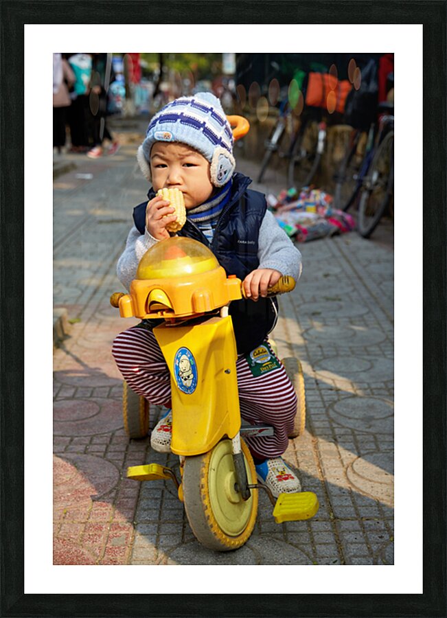 Child enjoys snack while riding tricycle in Hanoi streets Picture Frame print
