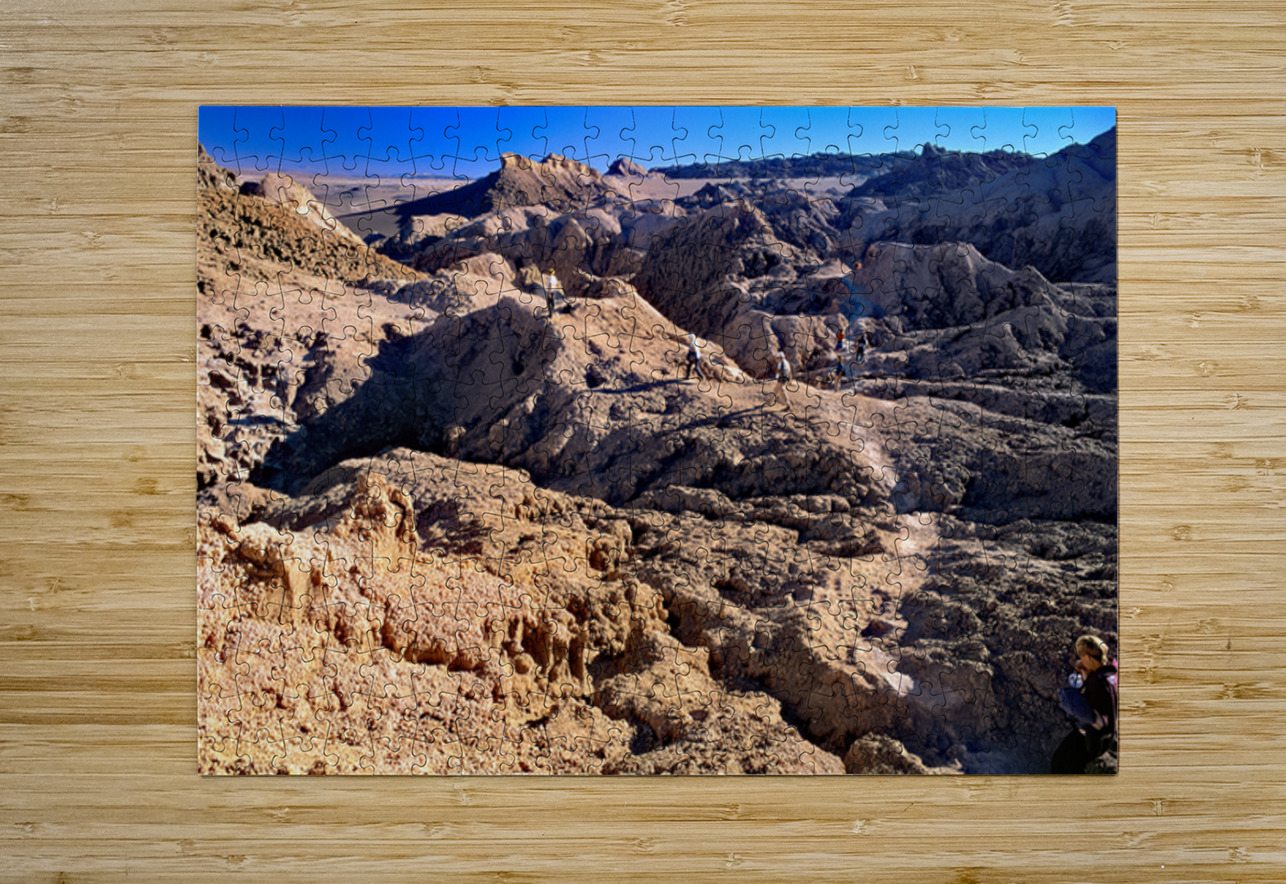 Hikers traverse a vast arid rocky desert landscape. Marco Brivio Puzzle printing