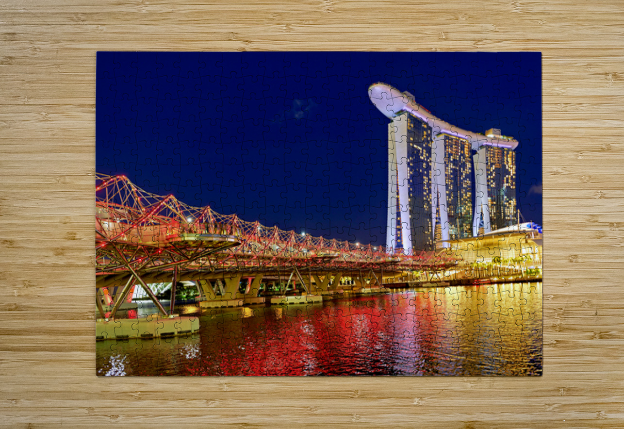People walk across the Helix Bridge as the Marina Bay Sands Hotel shines at sunset. The sky turns orange and lights reflect in the water. Marco Brivio Puzzle printing