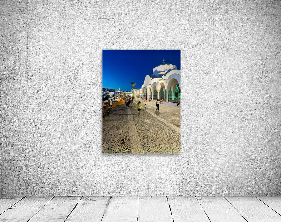 Santorinis iconic white church and bustling street at dusk. Wall Preview