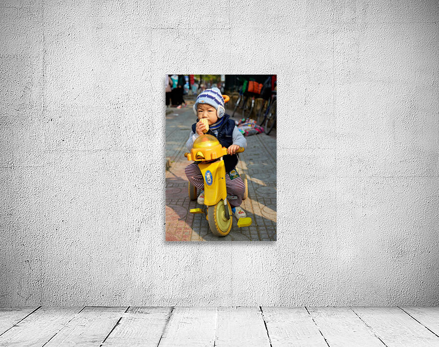 Child enjoys snack while riding tricycle in Hanoi streets Wall Preview