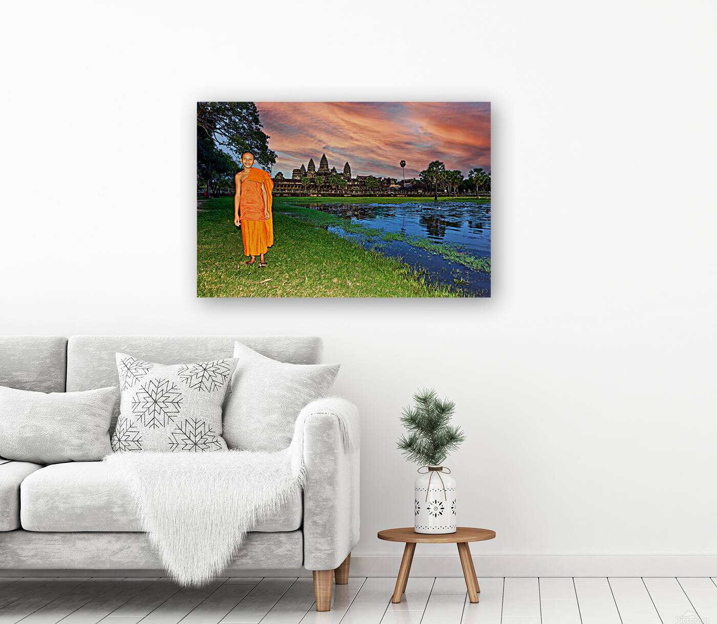 Monk stands by pond with Angkor Wat and sunset sky. Reproduction