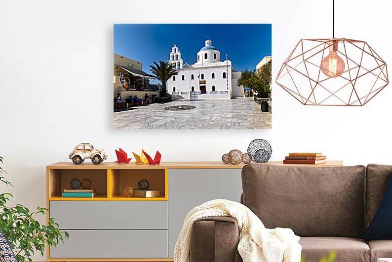 White Greek church with blue dome in sunny town square. by Marco Brivio
