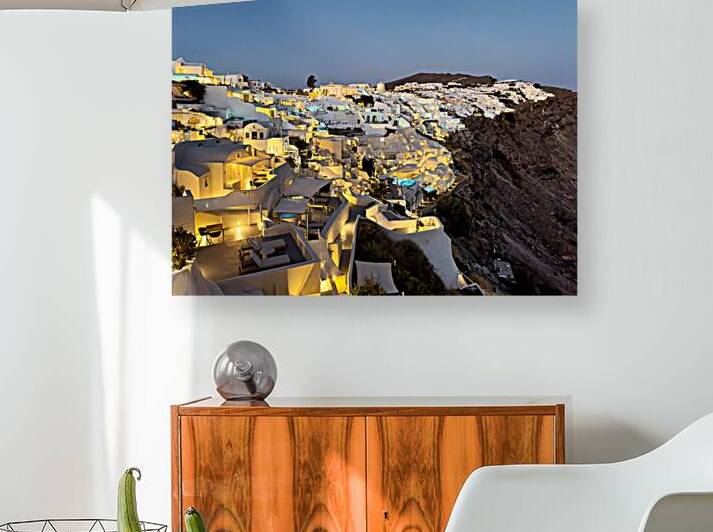 Illuminated white village on Santorini cliffside. by Marco Brivio