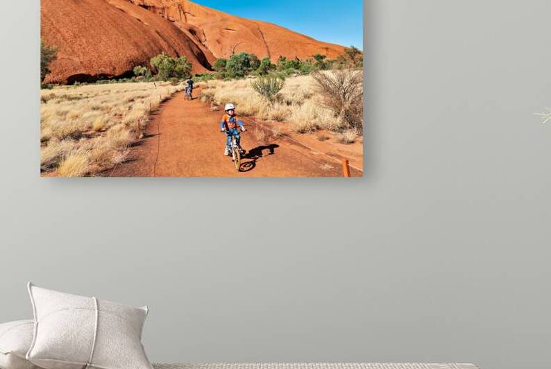 Children cycle near Uluru in Australias Northern Territory. by Marco Brivio