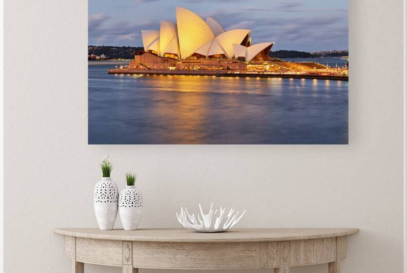 Sydney Opera House illuminated at dusk with harbor reflections. by Marco Brivio