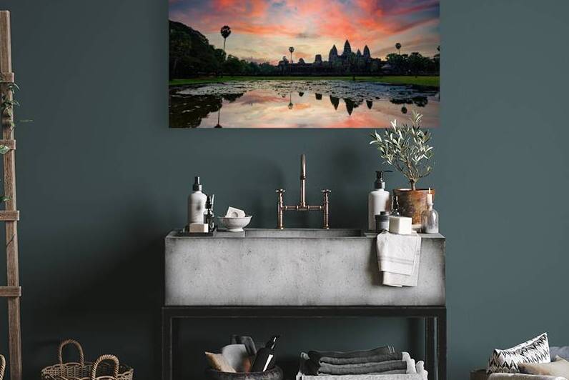 Vibrant sunset sky reflects over ancient Angkor Wat temple. by Marco Brivio