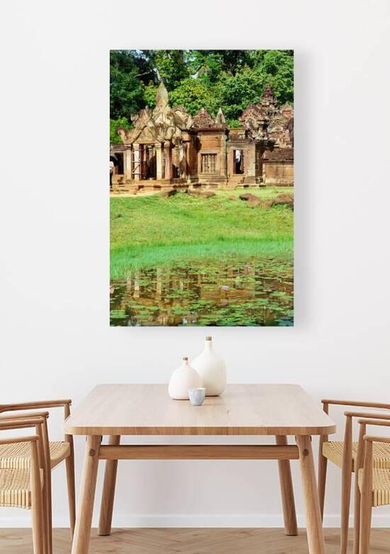 Ancient Cambodian temple reflected in a pond with water lilies. by Marco Brivio