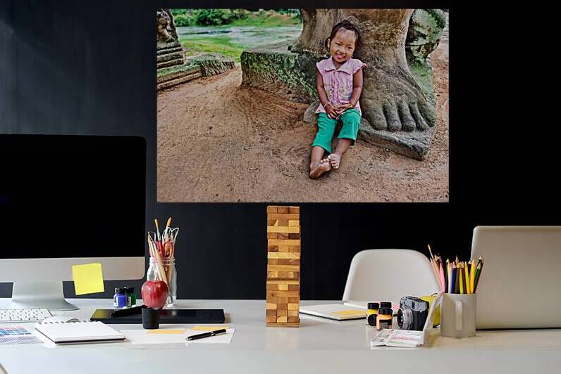 Smiling girl sits by ancient stone structure. by Marco Brivio