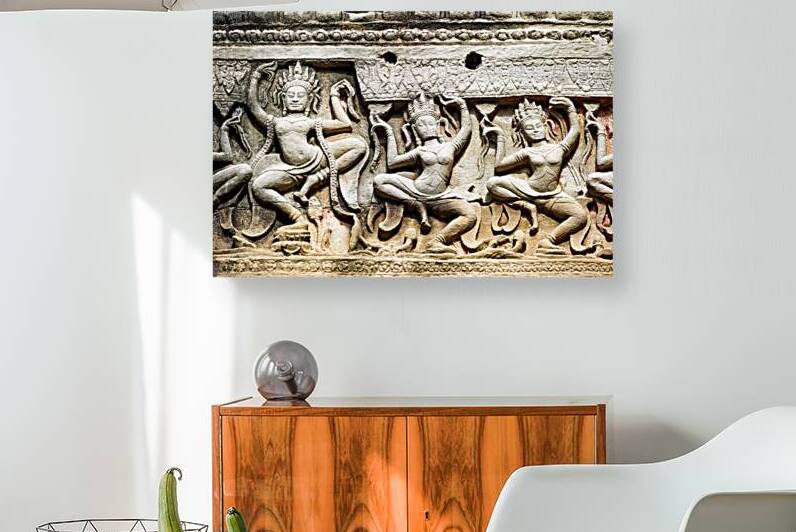 Ancient stone carvings of dancing Apsaras on a temple wall. by Marco Brivio