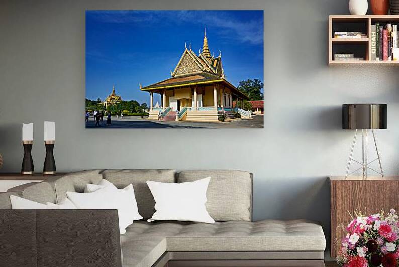 Ornate Cambodian temple under clear blue sky with visitors. by Marco Brivio