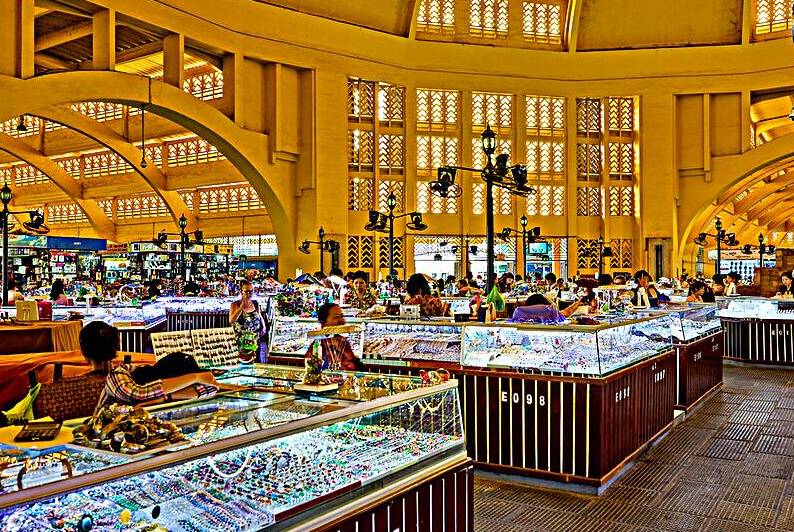 Bustling market with jewelry stalls and ornate architecture. by Marco Brivio