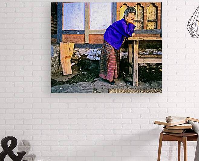 Smiling elderly woman in traditional dress leaning on wooden tab by Marco Brivio