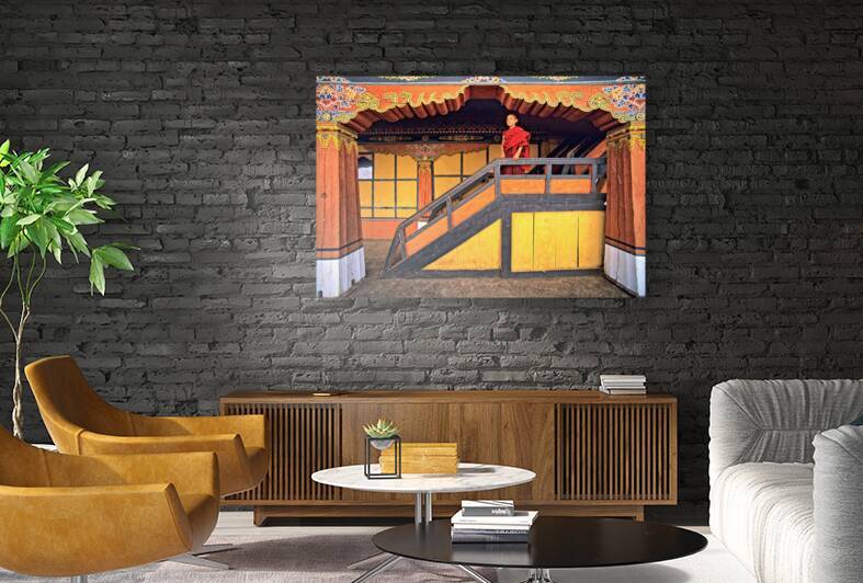 Young monk in red robes on colorful temple staircase. by Marco Brivio