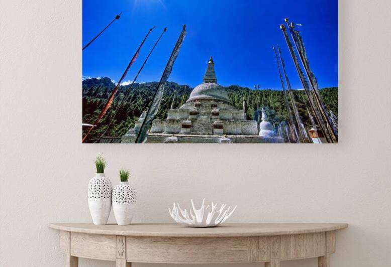 Buddhist stupa and prayer flags against a bright blue sky. by Marco Brivio
