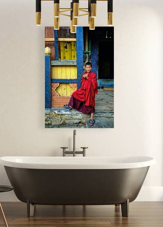 Smiling young monk in red robes at colorful traditional building by Marco Brivio