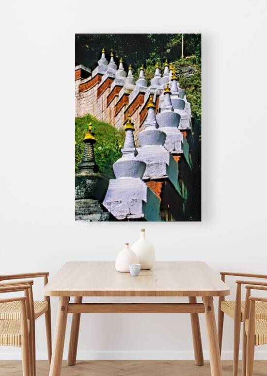 White stupas with golden spires on a green hillside. by Marco Brivio