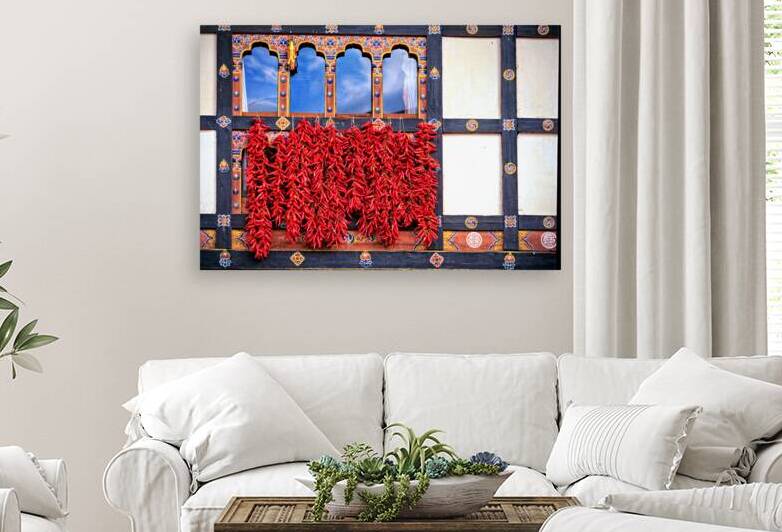 Vibrant red chilies hang from a decorated Bhutanese window. by Marco Brivio