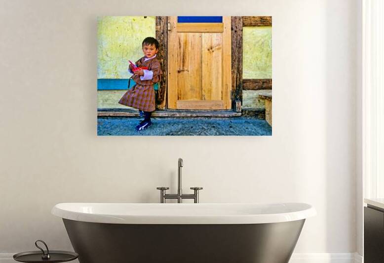 Bhutanese child in traditional dress holding a bowl and spoon. by Marco Brivio