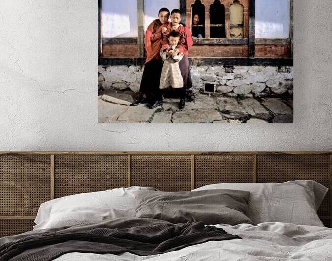 Children embracing one holding toy gun outside traditional bui by Marco Brivio